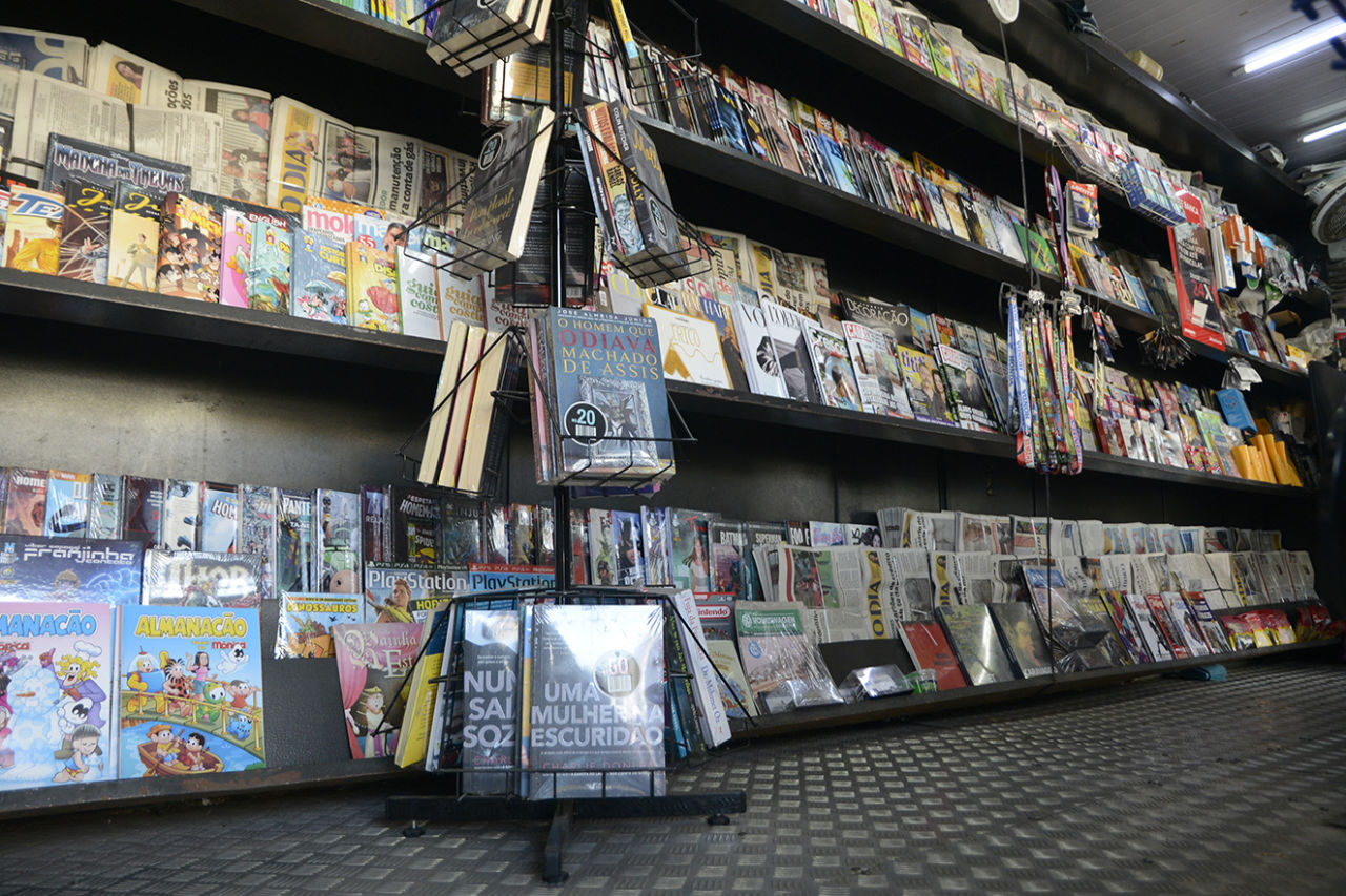 DESCRIÇÃO DA IMAGEM
Interior de uma banca de jornais com revistas nas prateleiras