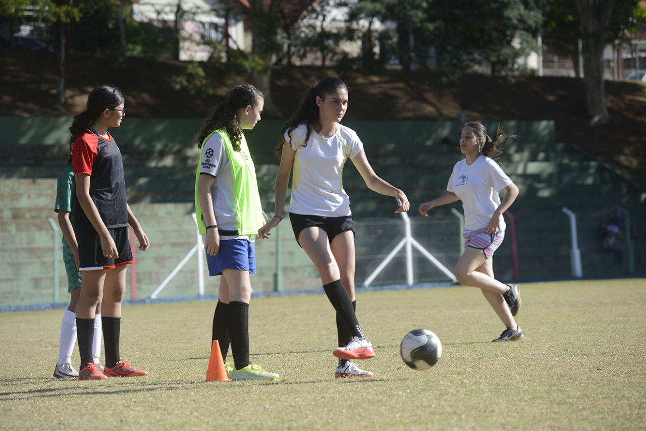 Atleta durante treino do futebol de campo, passando a bola para outra jogadora