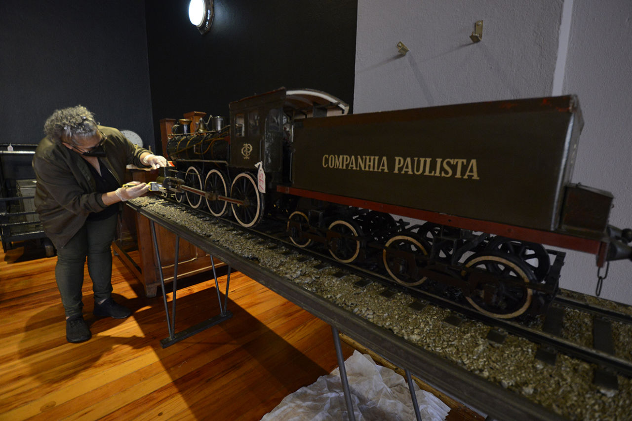 Mulher higieniza com pincel miniatura ferroviária, onde se lê "Companhia Paulista"