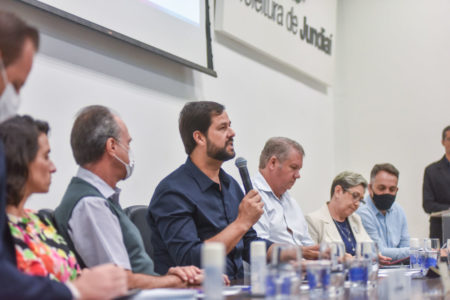 prefeito falando no microfone ao lado de demais participantes