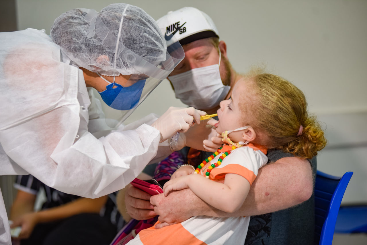 Médica escovando dente de paciente