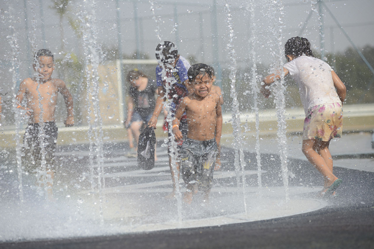 Crianças brincando em meio a chafariz de água