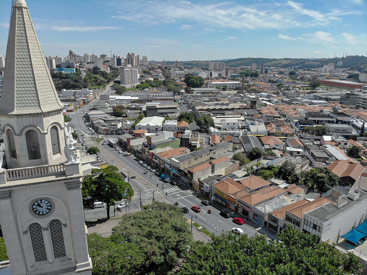 Foto aérea do bairro da vila Arens de Jundiaí, em que se veem a torre da igreja à esquerda e as ruas, telhados e copas das árvores