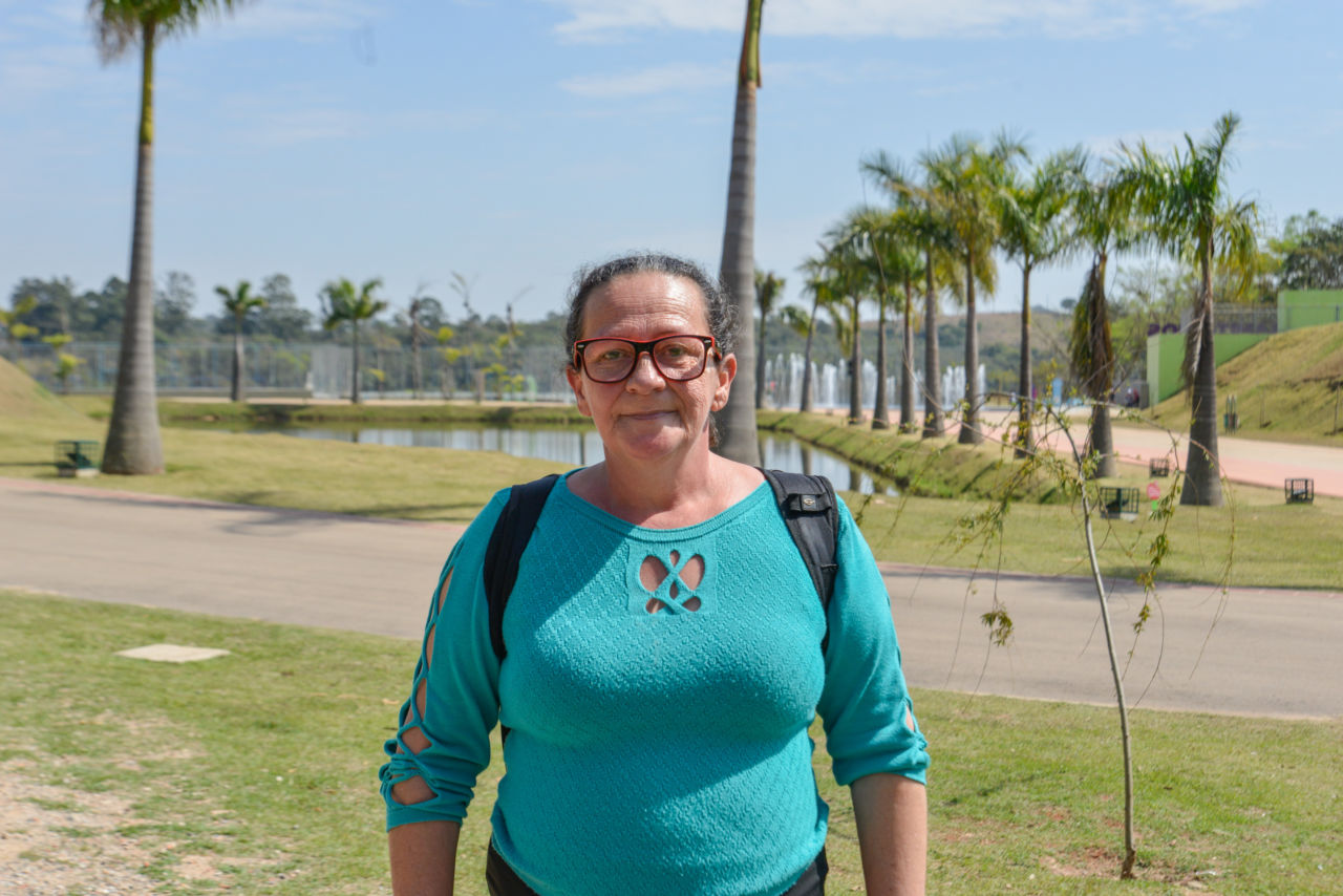 Nesta imagem contém uma senhora, que é aluna do nono ano do CMEJA. Ela veste uma blusa verde com detalhes nas mangas, e usa óculos quadrado nas cores vermelho e preto. 