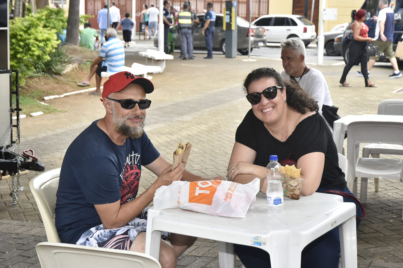 Cléber e Thaisa fazem uma pausa nas comprar para comer um pastel na Praça da Matriz