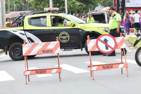 Na foto, agentes de trânsito estão em rua interditada para desfile de bloco de Carnaval, monitorando o movimento para garantir segurança para foliões.