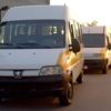 Na foto, há três vans utilizadas para transporte escolar de estudantes estacionadas em frente a uma escola de Jundiaí.