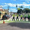 Na imagem estão os mascotes da Unidade de Gestão de Mobilidade e Transporte (UGMT), Vaguinho e Julinha, acompanhados de agentes de trânsito que atuam nas orientações nas escolas para incentivar de forma lúdica a travessia segura na faixa de pedestres.