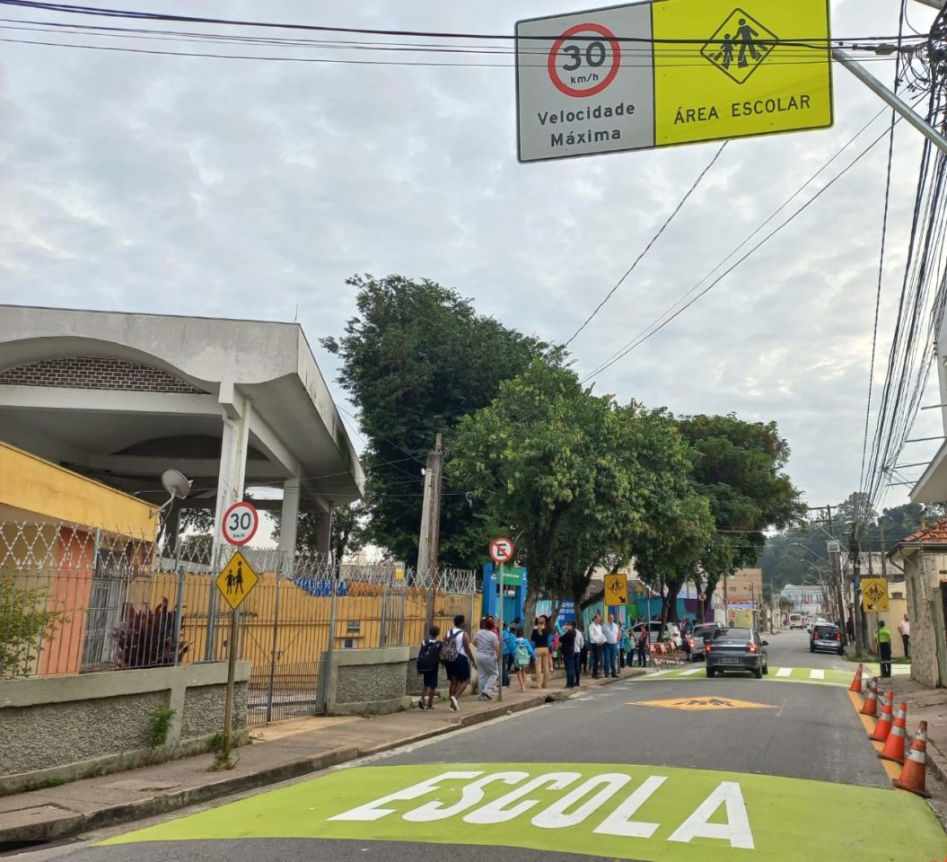 Na imagem, estão pintadas faixas na cor lima-limão com listras brancas e a palavra 'Escola', indicando ser preciso atenção por ser uma área escolar, no caso, a EMEB Pedro de Oliveira.
