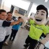 Na imagem, o mascote Vaguinho dá as mãos para os alunos que participaram da ação na EMEB Antonino Messina sobre as regras e equipamentos de segurança de trânsito.