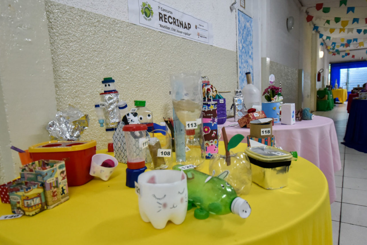 Foto da mesa com os brinquedos de materiais recicláveis criados pelos alunos. 
