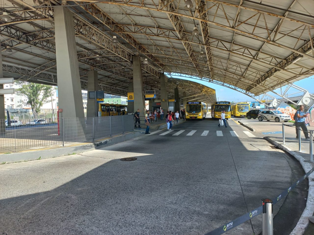 Na imagem, está o Terminal Vila Arens com ônibus e usuários que atravessam na faixa de pedestre. Os novos itinerários sairão do Terminal Vila Arens, e irão seguir para a Vila Nambi.