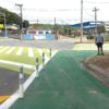A imagem mostra um morador do Jardim Guanabara, Lucas, que está na calçada e ao lado estão duas faixas de travessia lima-limão e a pintura de ampliação de passeio na cor verde bandeira para trazer mais acessibilidade aos pedestres e ciclistas.