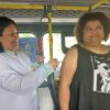 A imagem mostra uma enfermeira aplicando vacina em uma senhora dentro do ônibus que é utilizado para o programa Qualidade de Vida nos Terminais.