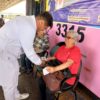 A imagem mostra um enfermeiro aferindo a pressão arterial de uma senhora na plataforma do Terminal Vila Arens.