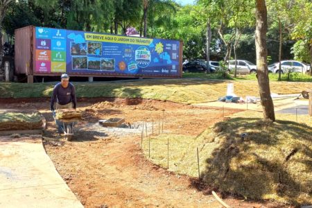 Na imagem está um painel no alto sobre um container com fotos das etapas da obra do Jardim do Trânsito e QR Code para acesso às informações.