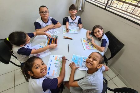 Na imagem, estão seis crianças que estudam em uma escola da rede municipal de Jundiaí. Elas estão com lápis coloridos em uma das mão para pintar desenhos com carros, ruas, pessoas, semáforos para o Concurso de Desenho do Maio Amarelo.