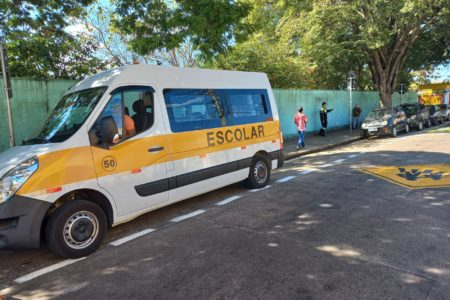 A imagem mostra uma van escolar estacionada em frente a uma escola na Vila Rio Branco, tem também crianças andando na calçada. É para informar que tem inscrições abertas até 30 de setembro para alvará de transporte escolar.